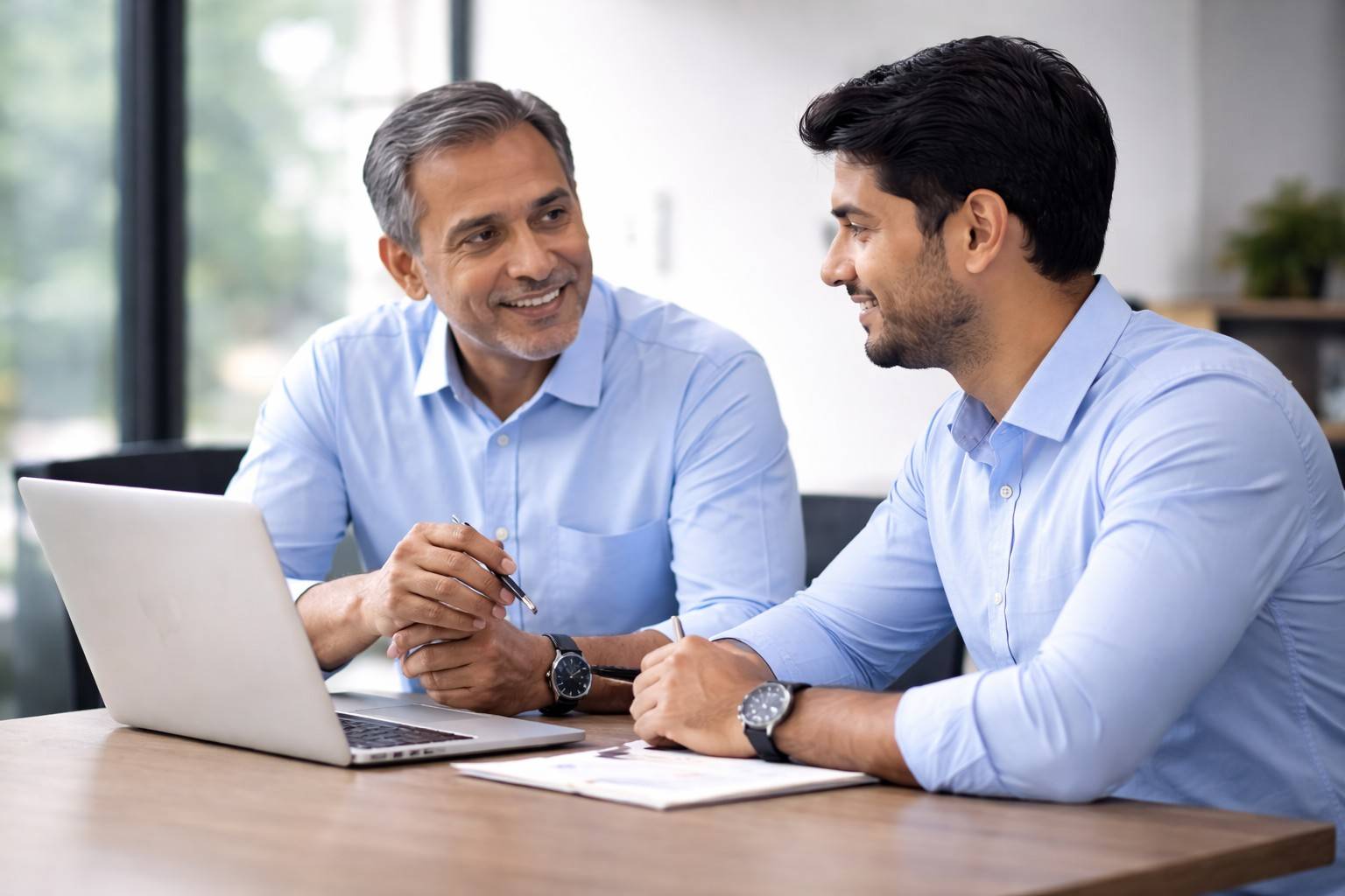 An experienced mentor reviewing work on a laptop with a younger colleague